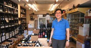 東京・大田区、久が原駅南口にある秋庭商店（あきばしょうてん）にて撮影。笑顔の人が店主、小日向（おびなた）さんです。この方は頼りになります。手頃な価格の、自然な味のワインをわかりやすく薦めてくれます。これからのライフデザインを提案するブログ「みらいメモ：暮らしと仕事を200字で」の記事「ワインの上手な選び方　- 秘訣は人です –」のOGP画像です。企画制作・矢嶋剛（綴り手　矢嶋ストーリーtokyo）。